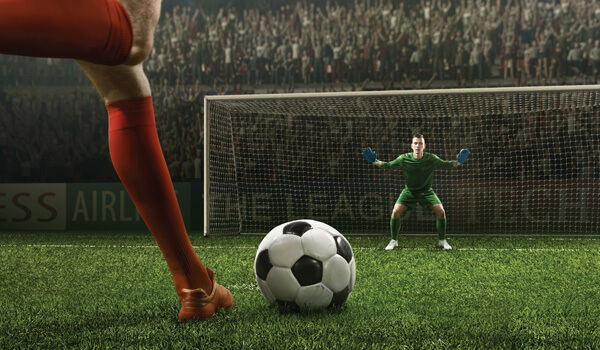 Soccer player about to kick a ball toward a waiting goalie in a goal