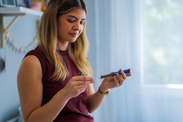 Woman prepares to take a GLP-1 injection.